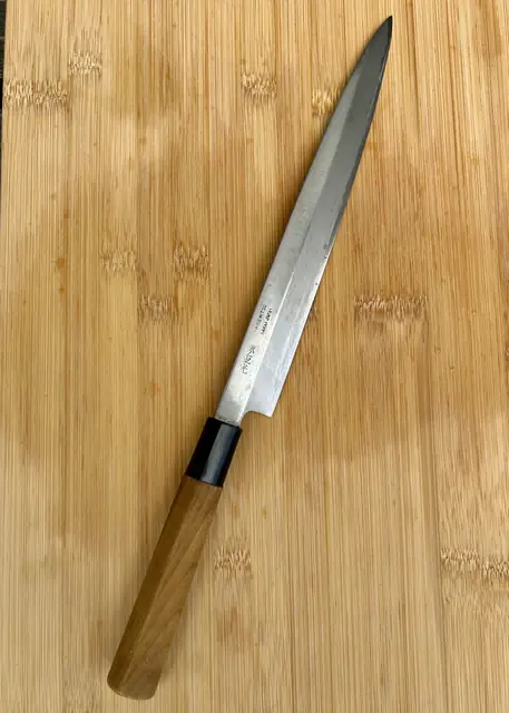 Dun Japans mes met houten handvat op een houten snijplank
